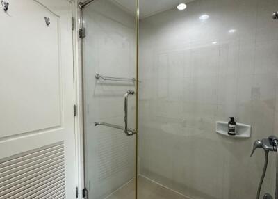 Modern bathroom with glass shower enclosure, tiled walls, and door hooks