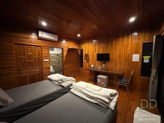 Spacious wooden-clad bedroom with twin beds and a desk area