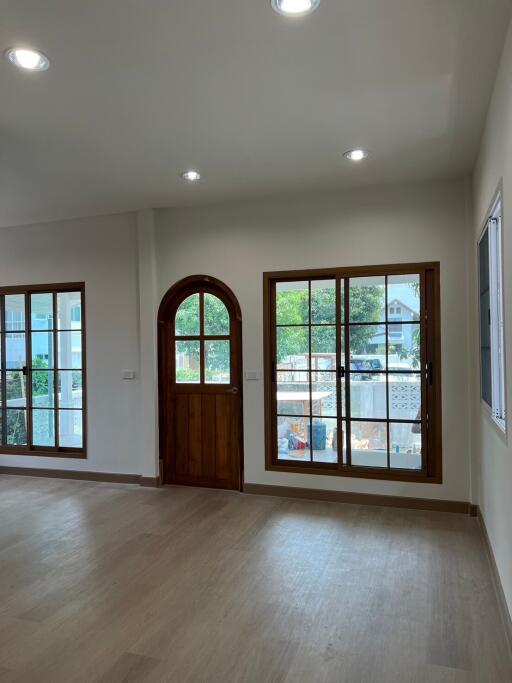 Spacious living room with large windows and wooden door