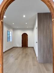 spacious living room with wooden flooring and arched doorway