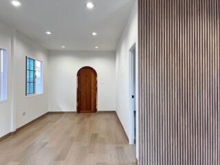 Spacious living area with wooden flooring and arched wooden door