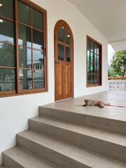 Front entrance with large wooden door and windows, steps leading to the entrance