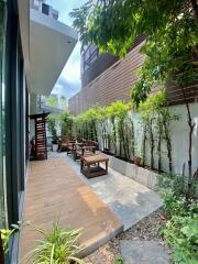 Modern outdoor patio with wooden seating and lush greenery