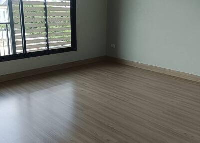 Empty bedroom with large window and wooden flooring