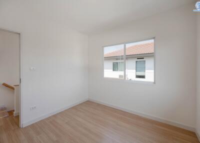 Empty bedroom with a window and wooden floor