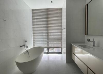 Modern bathroom with freestanding bathtub and large window.