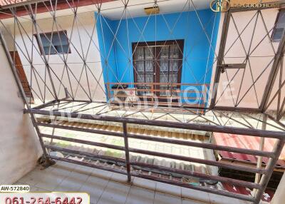 Outdoor balcony area with a metal railing and a view of a building with a blue and white exterior