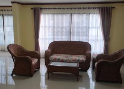 Spacious living room with rattan furniture and large windows.