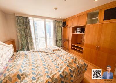 Spacious bedroom with large windows and built-in wooden wardrobe