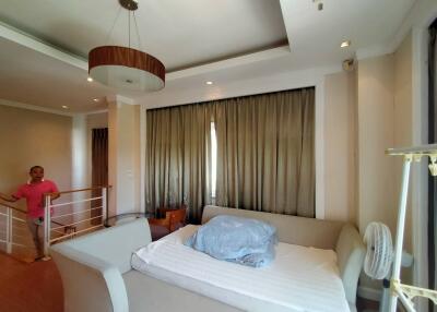 Bedroom with large bed, modern light fixture, and grey curtains