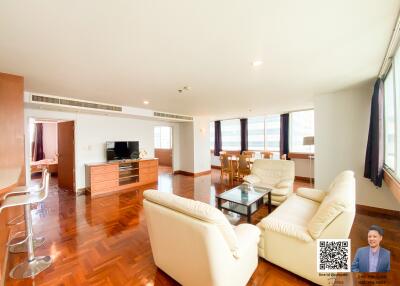 Spacious living room with white sofas, wooden floor, dining area, and a modern kitchen