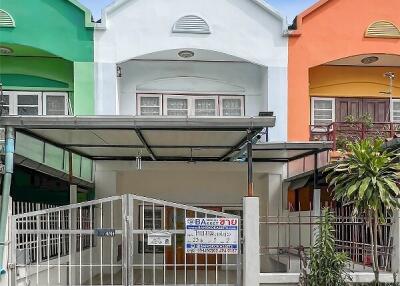 Front view of colorful row houses with a covered parking area and a gate