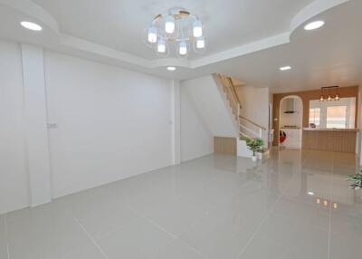 Spacious, modern living room with chandelier and view into kitchen