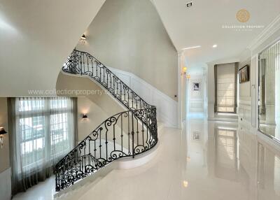 Elegant hallway with wrought iron staircase and large windows