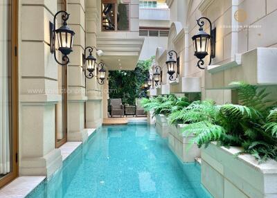 Elegant narrow swimming pool with plants and wall lanterns