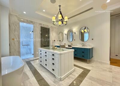 Spacious bathroom with white marble flooring, freestanding bathtub, double vanity and large mirrors