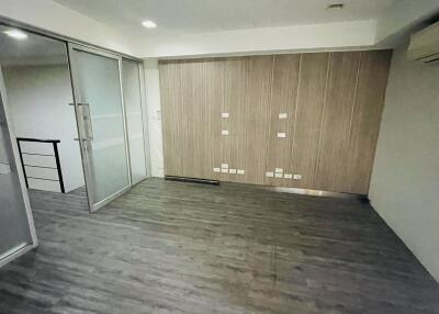 Unfurnished room with wooden flooring, glass partition, and air conditioning unit