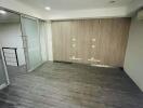 Unfurnished room with wooden flooring, glass partition, and air conditioning unit