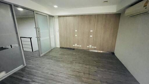 Unfurnished room with wooden flooring, glass partition, and air conditioning unit