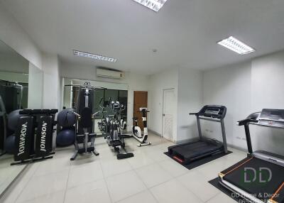 A modern fitness room with various exercise equipment, including treadmills, exercise bikes, and weights.