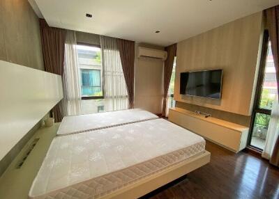 Modern bedroom with two beds, wall-mounted TV, air conditioning, and large windows