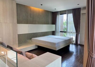 Modern bedroom with large bed, curtains, and wooden flooring