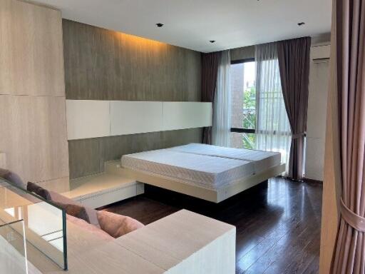 Modern bedroom with large bed, curtains, and wooden flooring