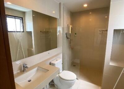 Modern bathroom with a large vanity mirror, toilet, sink, and walk-in shower