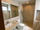 Modern bathroom with a large vanity mirror, toilet, sink, and walk-in shower