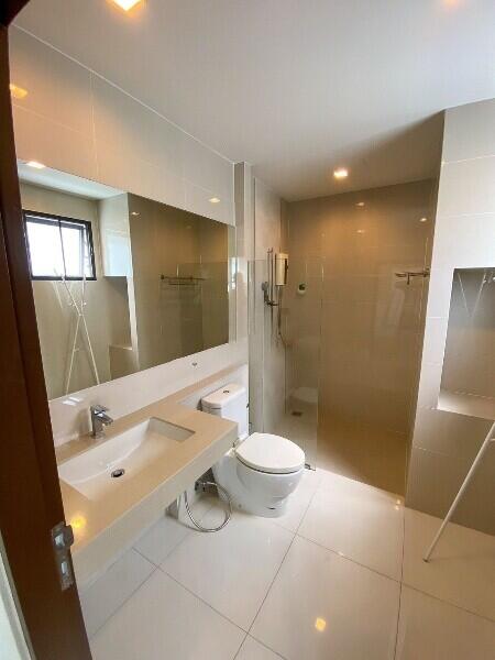 Modern bathroom with a large vanity mirror, toilet, sink, and walk-in shower