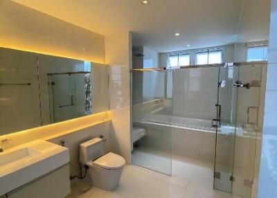 Modern bathroom with glass shower enclosure, wall-mounted sink, and toilet