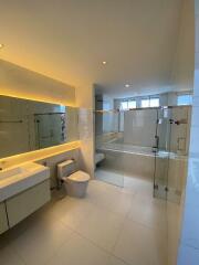 Modern bathroom with glass shower enclosure, wall-mounted sink, and toilet