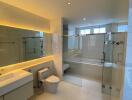 Modern bathroom with glass shower enclosure, wall-mounted sink, and toilet