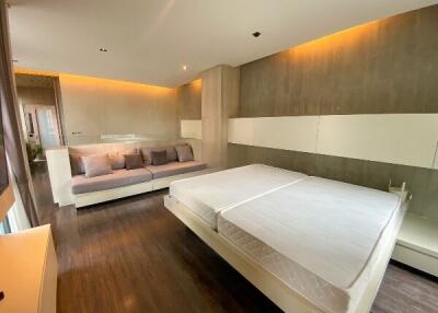 Modern bedroom with wooden flooring, double bed, and sofa