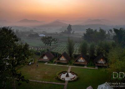 Scenic view of a landscape at sunset, with cabins and green fields