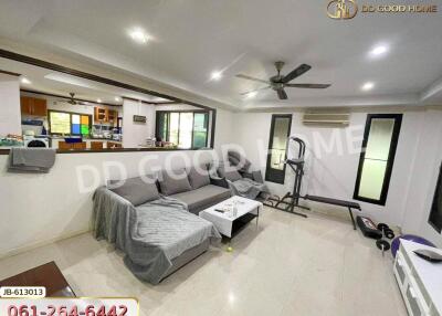 Spacious living room with a sectional sofa, ceiling fan, and adjacent kitchen