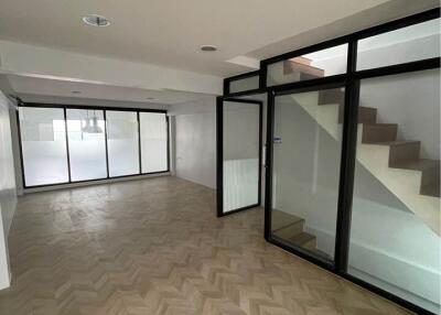 Spacious living room with large glass windows, modern staircase, and wooden flooring