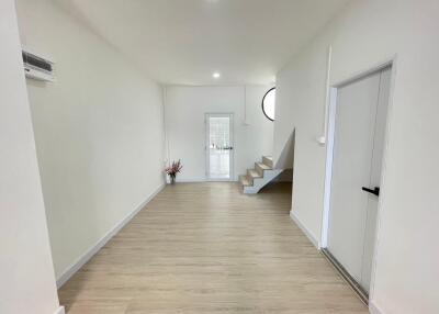 Main living space with wooden flooring, white walls, and staircase