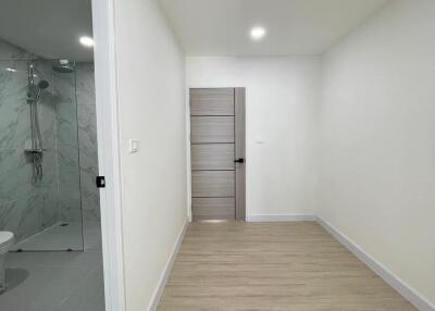 Bright hallway with wooden floor leading to a bathroom