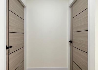 Minimalist hallway with wooden doors and light-colored flooring