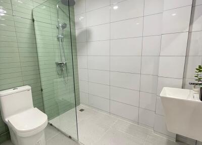 Modern bathroom with glass shower and green-tiled wall