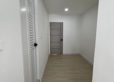 A modern hallway with wooden floor and recessed lighting