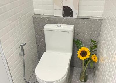 Modern bathroom with tiled walls and a sunflower in a glass vase