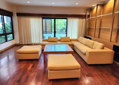 Spacious living room with wooden flooring, large windows, and contemporary furniture