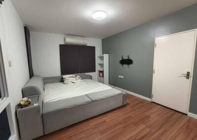 Bedroom with grey walls, wooden flooring, and a large bed