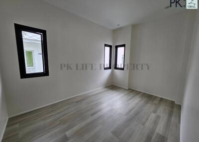 Spacious empty bedroom with wooden flooring and three windows