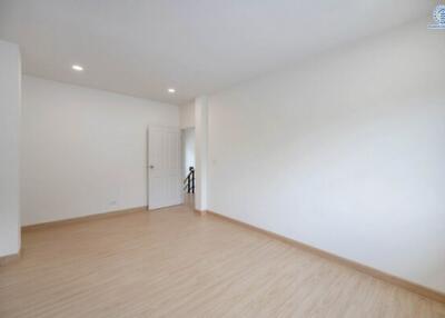 Spacious empty bedroom with wooden flooring, white walls, and recessed lighting