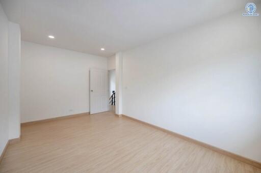 Spacious empty bedroom with wooden flooring, white walls, and recessed lighting