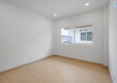 Spacious bedroom with wooden flooring and large window