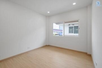 Spacious bedroom with wooden flooring and large window